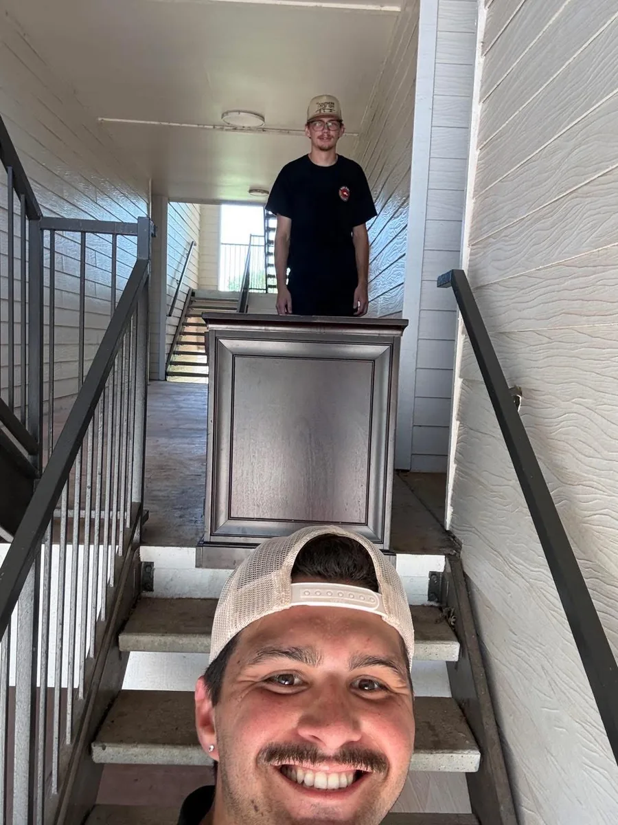 Red Dirt movers carefully carrying a dresser up the stairs during a home move